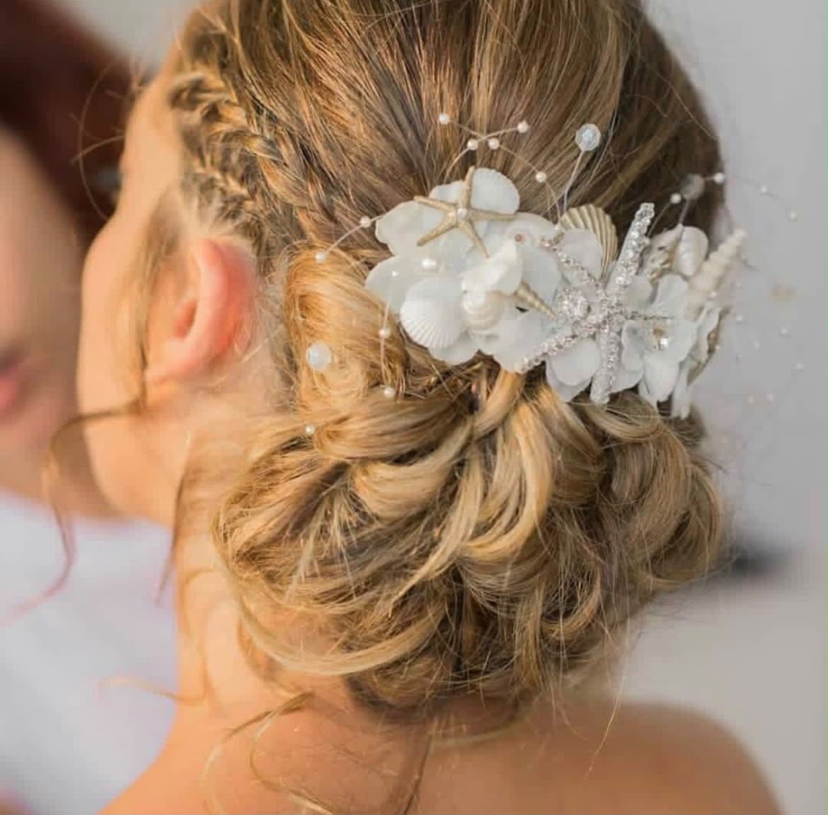 Bridal hair by Lee Elrom — braided low updo with a starfish and shell hairpiece